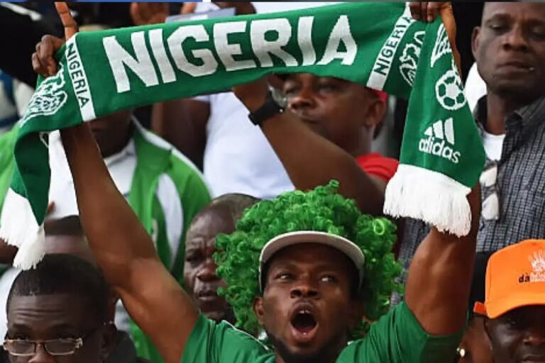 Supporter nigérian brandissant une écharpe « Nigeria » dans les tribunes d’un stade lors d’un match international.